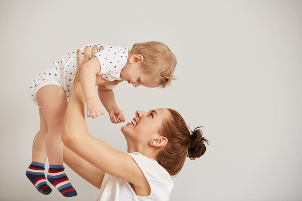 Young mother playing with her little baby bed 2